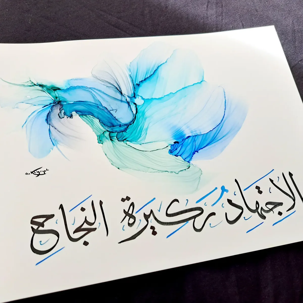 Black Arabic calligraphy over a wave of blue ink